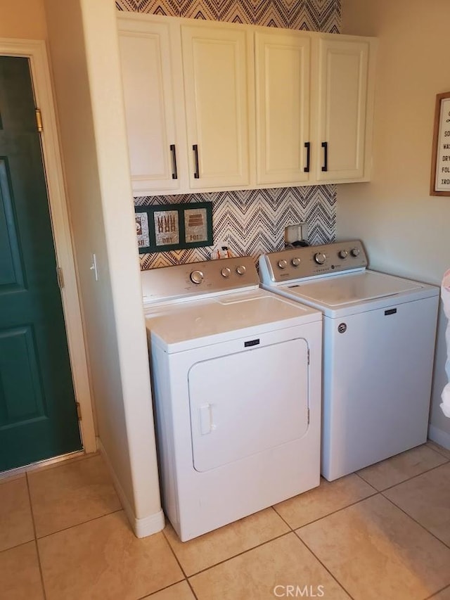 washroom featuring separate washer and dryer, light tile patterned flooring, cabinet space, and baseboards