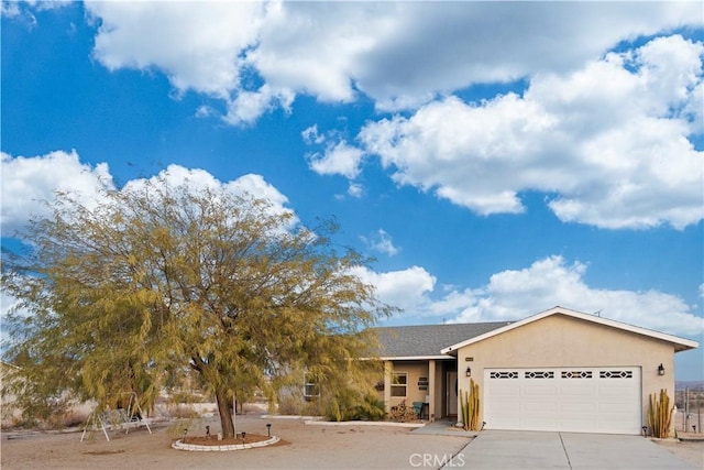 view of front of property featuring stucco siding, concrete driveway, and a garage