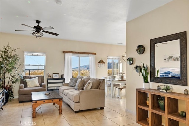 living area featuring light tile patterned flooring, baseboards, and ceiling fan