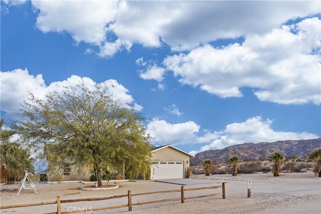 view of front of home with a garage, fence, a mountain view, and stucco siding