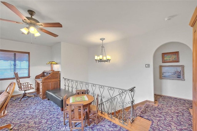 hall featuring arched walkways, a chandelier, and baseboards