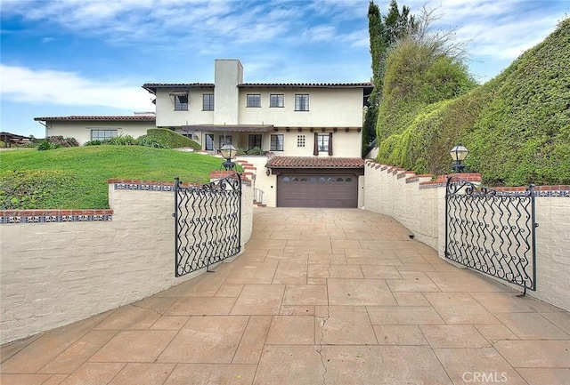 mediterranean / spanish-style house with a fenced front yard, stucco siding, a tiled roof, and concrete driveway