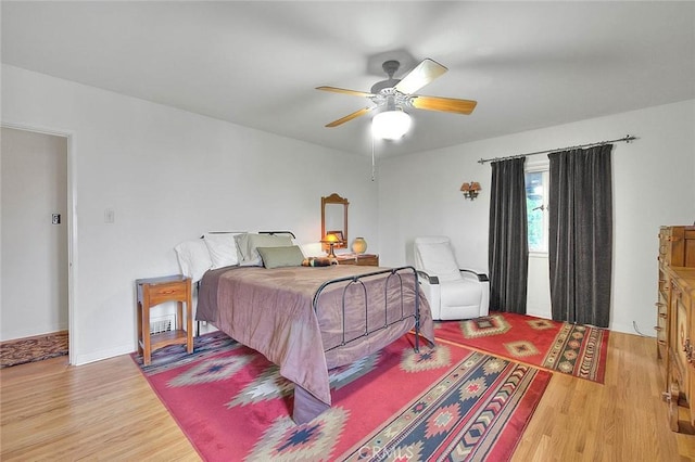 bedroom with light wood-style flooring, baseboards, and ceiling fan