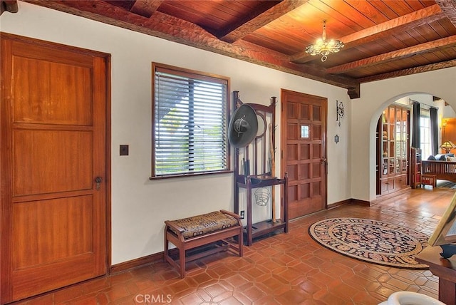 entryway featuring baseboards, arched walkways, beam ceiling, and wooden ceiling