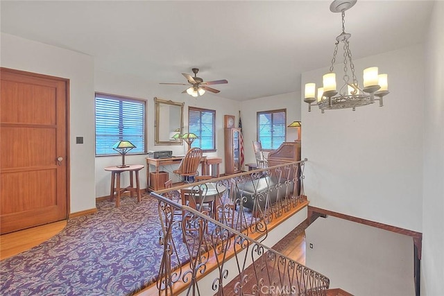 dining space featuring baseboards, wood finished floors, and ceiling fan with notable chandelier