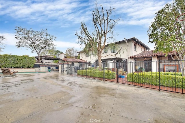 view of front of house with a tile roof, stucco siding, and fence private yard