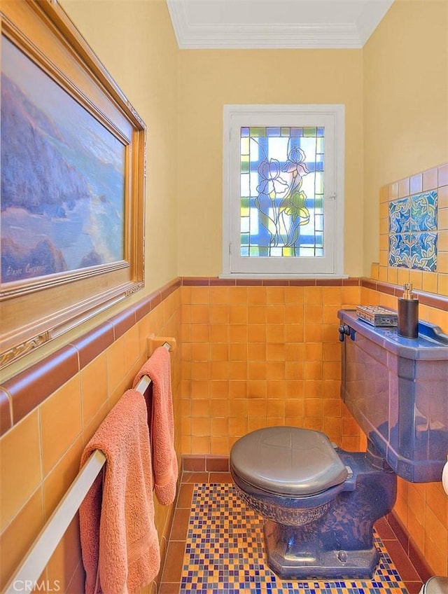 bathroom with a wainscoted wall, tile walls, crown molding, and tile patterned flooring