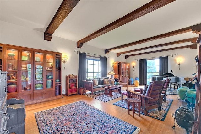 living area with beamed ceiling, a healthy amount of sunlight, and wood finished floors