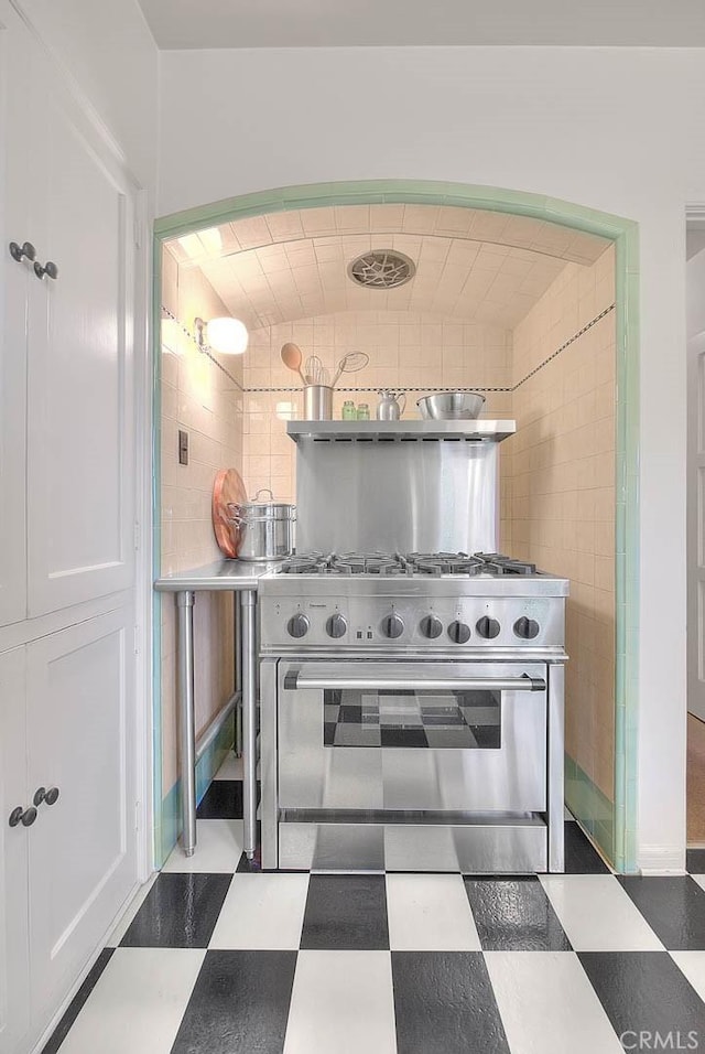 kitchen featuring tile patterned floors, high end range, and tile walls