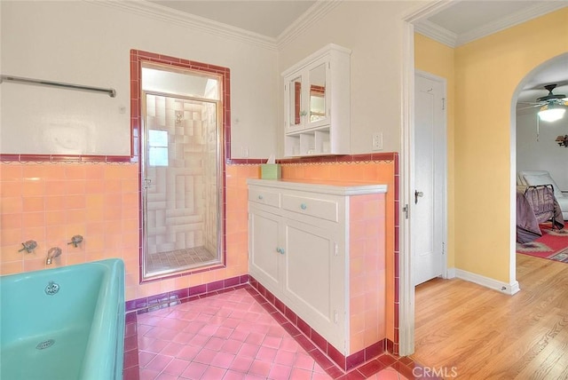 interior space featuring a garden tub, tile walls, a shower stall, and crown molding