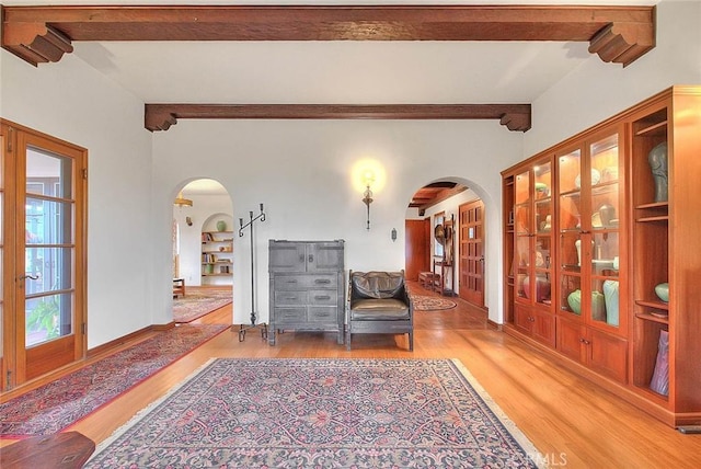 interior space with beamed ceiling, wood finished floors, and arched walkways