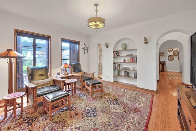 sitting room featuring built in features, wood finished floors, and arched walkways