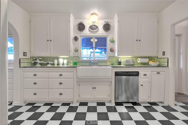 kitchen with light floors, a sink, tile counters, white cabinets, and stainless steel dishwasher