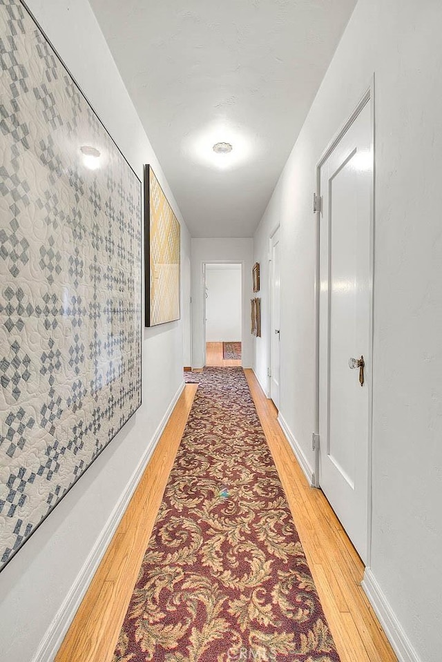 corridor with light wood-style flooring and baseboards