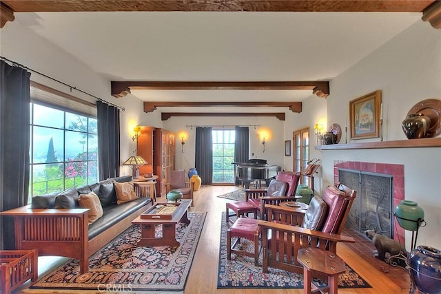 living room featuring beamed ceiling, wood finished floors, and a tile fireplace