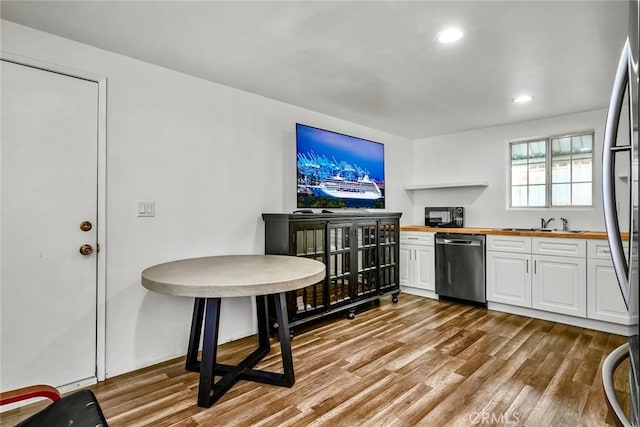 kitchen featuring wood finished floors, recessed lighting, appliances with stainless steel finishes, white cabinets, and wooden counters