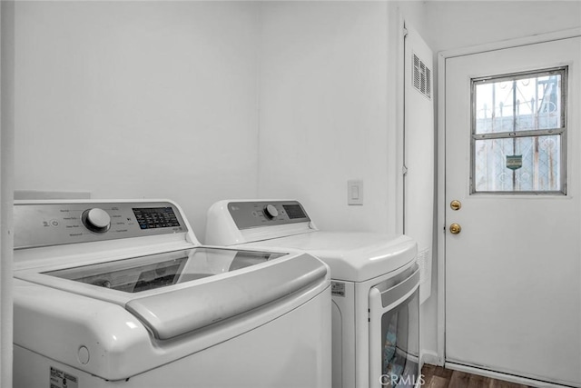 laundry room featuring washing machine and clothes dryer, laundry area, and wood finished floors