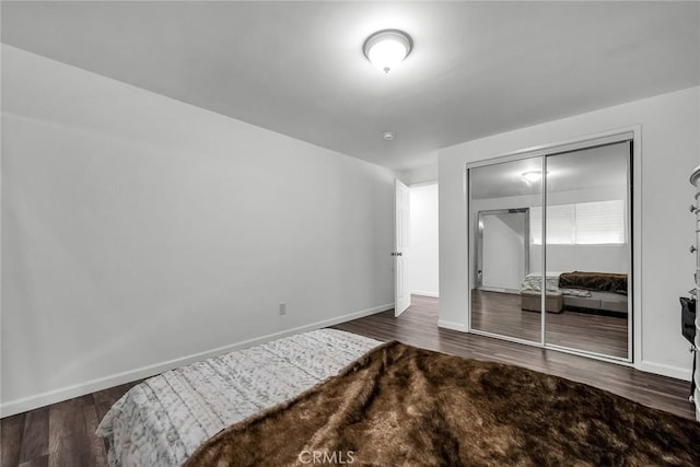 bedroom with a closet, baseboards, and wood finished floors