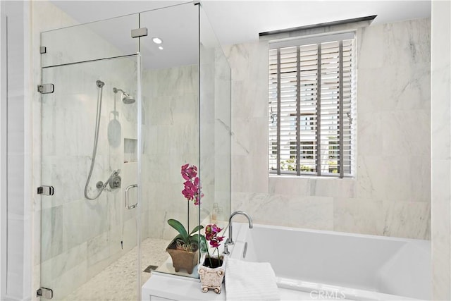 bathroom with a stall shower and a bath
