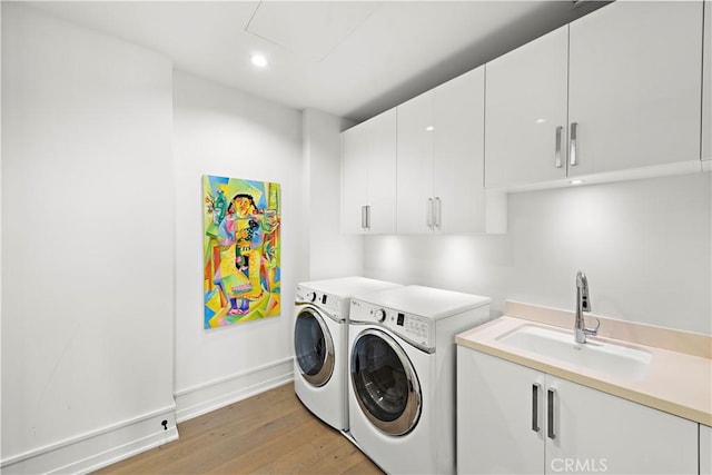 laundry room with washer and dryer, recessed lighting, cabinet space, a sink, and light wood-type flooring