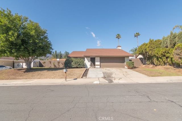 view of front of property with driveway, an attached garage, and fence