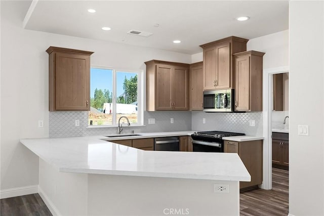 kitchen with stainless steel appliances, light countertops, visible vents, a sink, and a peninsula