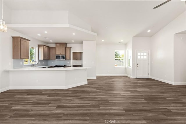 kitchen featuring dark wood-style flooring, stainless steel microwave, vaulted ceiling, and a sink