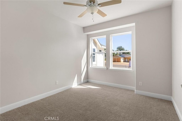 spare room featuring ceiling fan, carpet floors, and baseboards