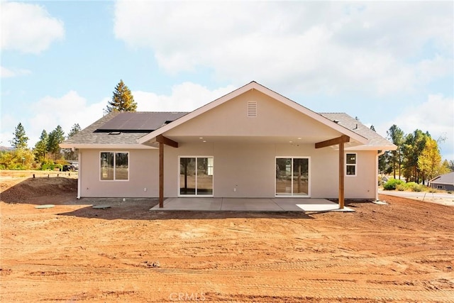 back of property featuring a patio area, solar panels, and stucco siding