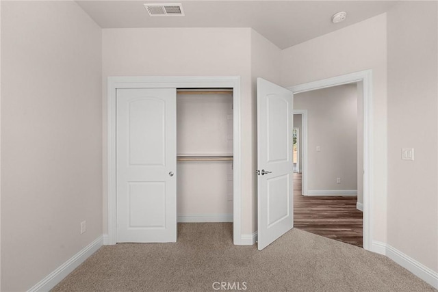 unfurnished bedroom with carpet floors, baseboards, visible vents, and a closet