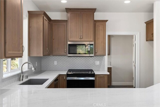 kitchen with recessed lighting, stainless steel microwave, backsplash, a sink, and black range with electric cooktop