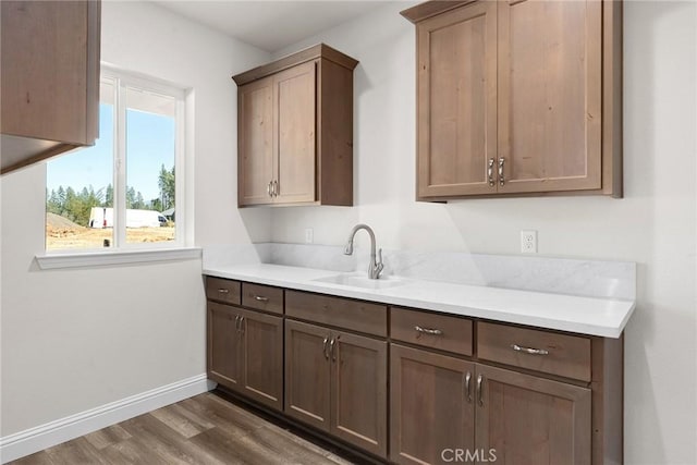 kitchen featuring dark wood-style floors, baseboards, light countertops, and a sink