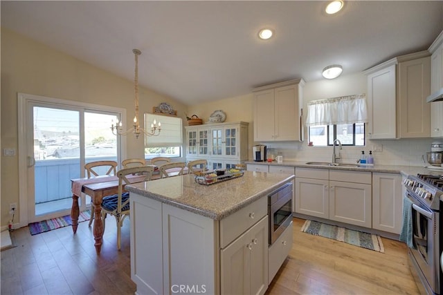 kitchen with a sink, backsplash, appliances with stainless steel finishes, and vaulted ceiling