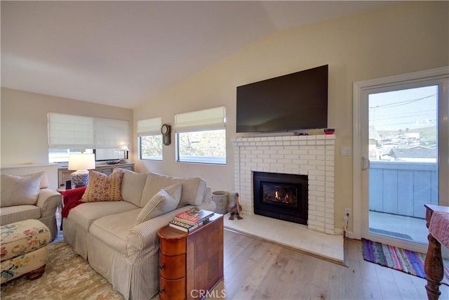 living area featuring a fireplace, wood finished floors, and vaulted ceiling