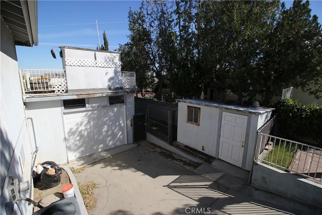 view of patio featuring a balcony, a storage shed, and an outbuilding