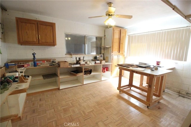 kitchen featuring ceiling fan, parquet floors, brown cabinets, open shelves, and concrete block wall