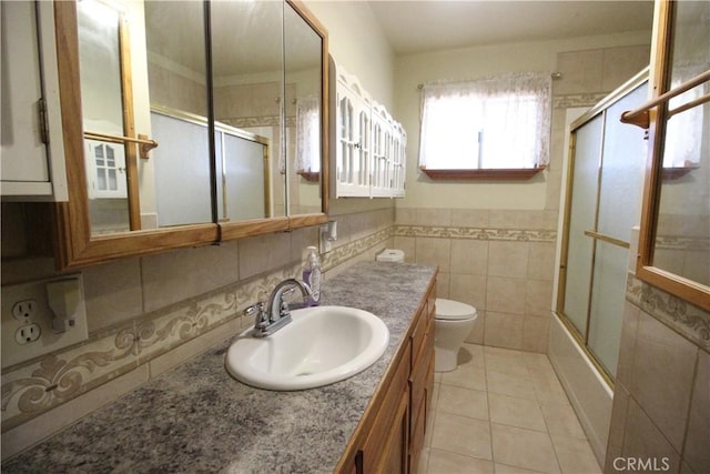 full bath featuring toilet, shower / bath combination with glass door, vanity, tile walls, and tile patterned floors