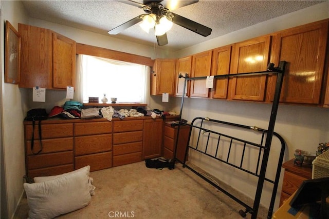 interior space with a ceiling fan, brown cabinets, and a textured ceiling