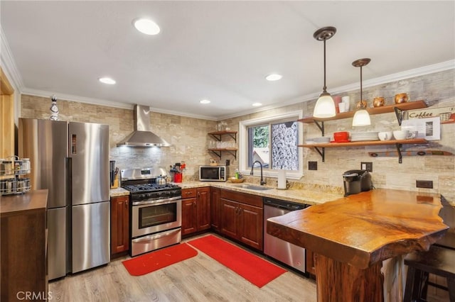 kitchen featuring ornamental molding, stainless steel appliances, wall chimney range hood, open shelves, and a sink