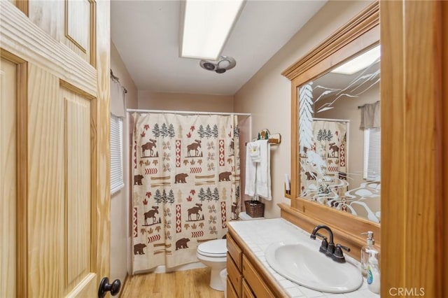 full bathroom featuring wood finished floors, a shower with shower curtain, vanity, and toilet