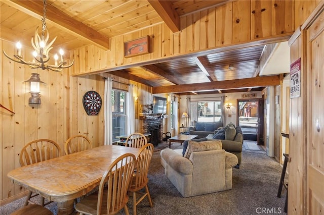 dining room featuring a fireplace with raised hearth, wood walls, wooden ceiling, and beam ceiling