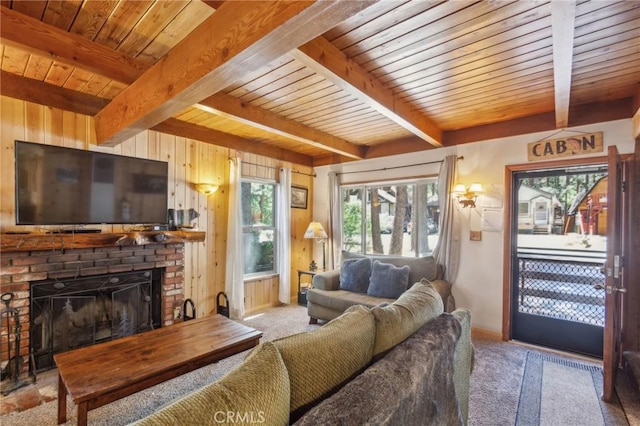 carpeted living area with beamed ceiling, wood walls, a brick fireplace, and wooden ceiling