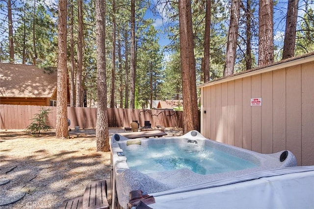 view of swimming pool featuring fence and a hot tub