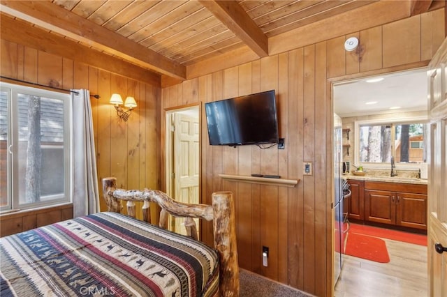 bedroom with a sink, wood ceiling, wooden walls, and beam ceiling