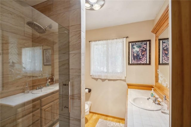 bathroom featuring tiled shower, vanity, toilet, and wood finished floors