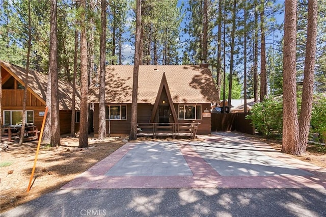 a-frame home featuring a shingled roof and aphalt driveway