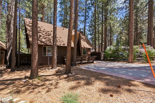 view of property exterior with a patio, fence, crawl space, roof with shingles, and a chimney