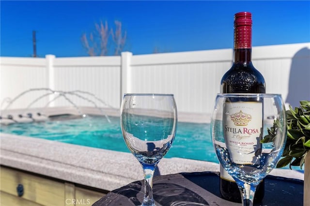 view of pool with a hot tub and fence