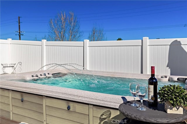 view of pool with fence and a hot tub