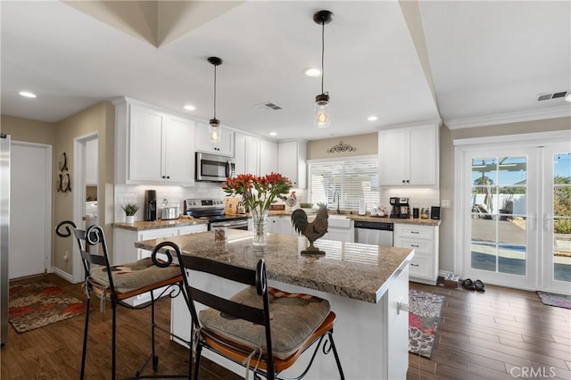 kitchen with visible vents, dark wood-style floors, white cabinetry, appliances with stainless steel finishes, and decorative backsplash